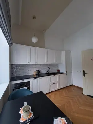 a kitchen with white cabinets and a table with a bowl on it at Vyduno apartamentai 11 in Kaunas