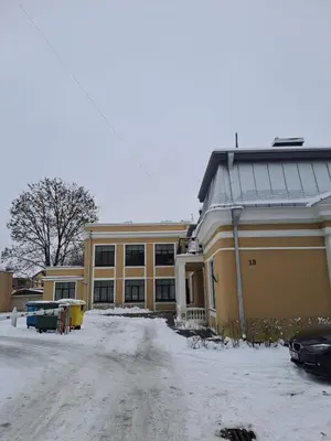 a large yellow building with snow on the ground at Vyduno apartamentai 11 in Kaunas
