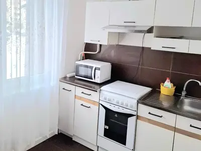 a kitchen with white cabinets and a microwave at Butas Putinuose in Alytus