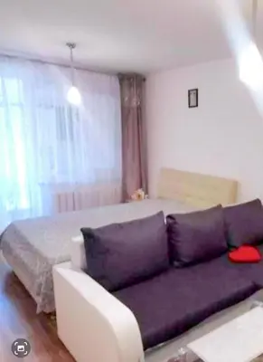 a living room with a purple couch in front of a bed at Butas Putinuose in Alytus