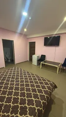 a room with a bed and a tv and chairs at Bernotiškių Hotel & Dining