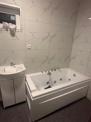 a white bathroom with a tub and a sink at Bernotiškių Hotel & Dining