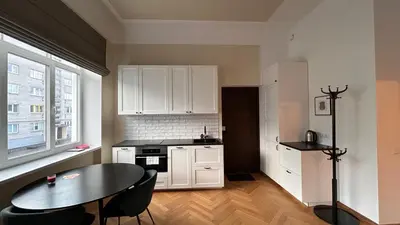 a kitchen with white cabinets and a table and a window at Vydūno apartamentai 12 in Kaunas