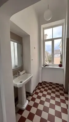 a bathroom with a sink and a window and a checkered floor at Vyduno apartments 9 in Kaunas