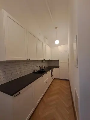 a kitchen with white cabinets and a black counter top at Vyduno apartments 9 in Kaunas
