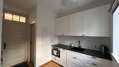 a kitchen with white cabinets and a sink and a door at Vyduno apartments 7 in Kaunas