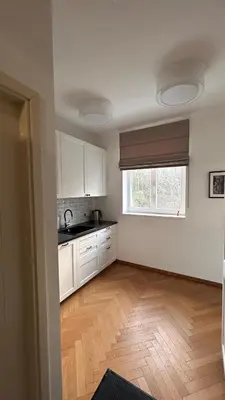 a kitchen with white cabinets and a wooden floor at Vyduno apartments 7 in Kaunas