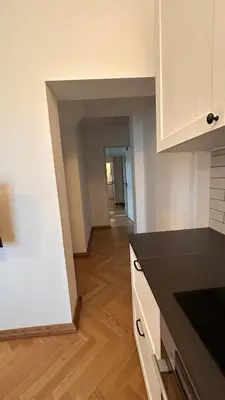 a kitchen with white walls and a wooden floor at Italian Embassy Suites 3 in Kaunas