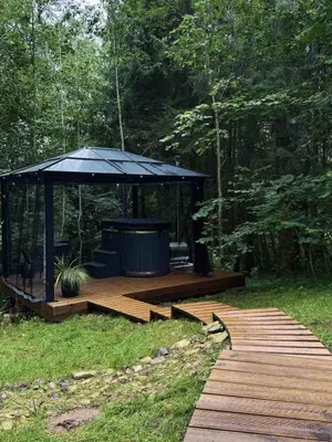 a wooden deck with a gazebo in the woods at Tyla dviese in Kaciūniškiai