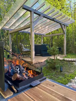 a pergola and a fire pit in a yard at Tyla dviese in Kaciūniškiai