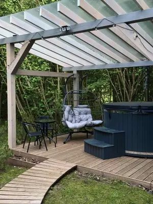 a pergola with a chair and a table on a deck at Tyla dviese in Kaciūniškiai