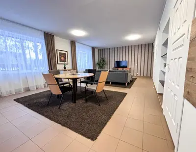 a living room with a table and chairs and a couch at XXL apartamentai su nemokamu parkingu in Šiauliai