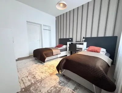 a bedroom with two beds and a desk in it at XXL apartamentai su nemokamu parkingu in Šiauliai