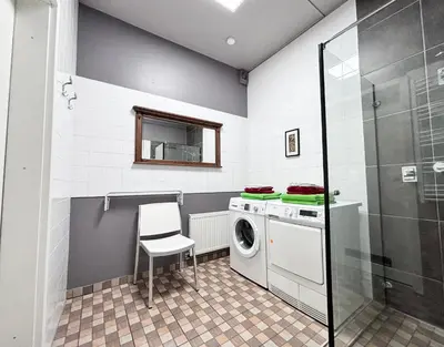 a laundry room with a washing machine and a chair at XXL apartamentai su nemokamu parkingu in Šiauliai