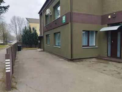a green building with a sidewalk in front of it at L apartamentai su nemokamu parkingu in Šiauliai