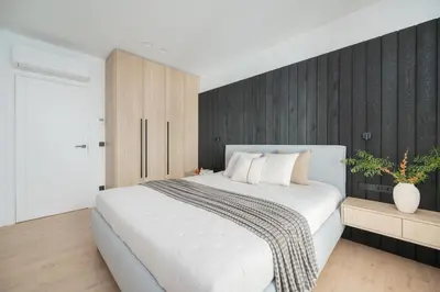 a bedroom with a white bed and a wooden wall at Modern cozy apartment with free parking in trendy Paupys in Vilnius