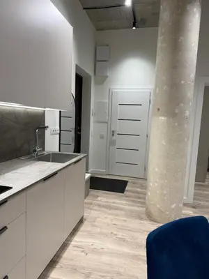 a kitchen with white cabinets and a column at Modern apartment near old town in Kaunas