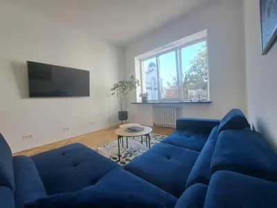 a living room with a blue couch and a table at Cathedral View Central Flat in Kaunas