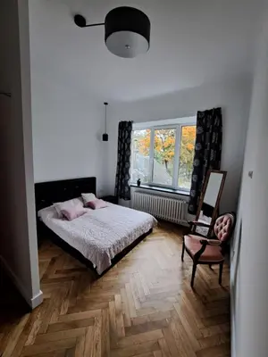 a bedroom with a bed and a chair and a window at Cathedral View Central Flat in Kaunas