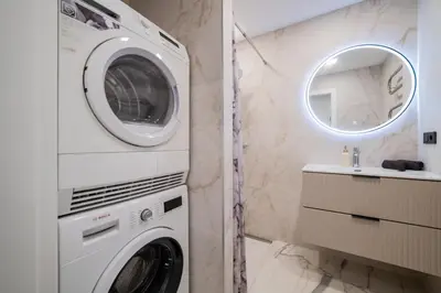 a washing machine in a bathroom with a mirror at ENZO Apartments in Šiauliai