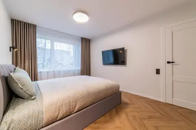 a bedroom with a bed and a tv on a wall at ENZO Apartments in Šiauliai
