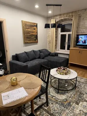 a living room with a couch and a table at Gates of Dawn luxury Apartment - Aušros Vartų apartamentai in Vilnius