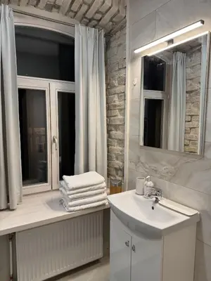 a white bathroom with a sink and a mirror at Gates of Dawn luxury Apartment - Aušros Vartų apartamentai in Vilnius