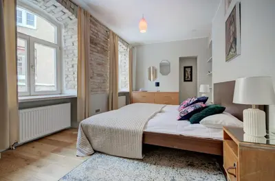 a bedroom with a large bed and a window at Gates of Dawn luxury Apartment - Aušros Vartų apartamentai in Vilnius