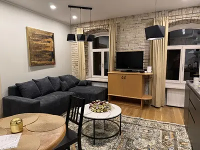 a living room with a couch and a tv at Gates of Dawn luxury Apartment - Aušros Vartų apartamentai in Vilnius