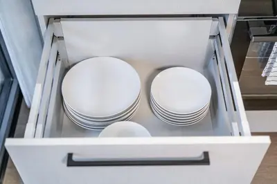 a white drawer with dishes in it at 2 Bedroom Green City View apartment by Reside Baltic in Vilnius