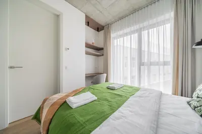 a bedroom with a large bed with a green blanket at 2 Bedroom Green City View apartment by Reside Baltic in Vilnius