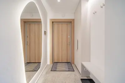 a hallway with two wooden doors and a mirror at 2 Bedroom Green City View apartment by Reside Baltic in Vilnius