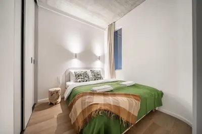 a bedroom with a bed with a green blanket at 2 Bedroom Green City View apartment by Reside Baltic in Vilnius