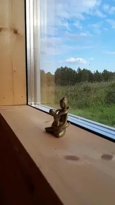 a small metal toy sitting on a window sill at namelis tyloje in Šarkiškės