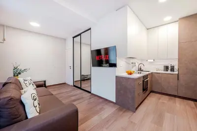 a living room with a couch and a kitchen at Center Gallery Apartment in Kaunas