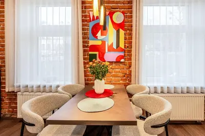 a dining room table with chairs and a vase with flowers at Center Gallery Apartment in Kaunas