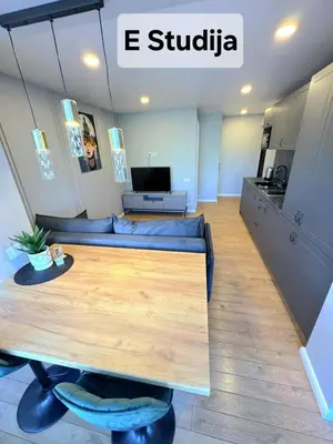 a living room with a table and a couch at Trumpalaikė butų nuoma Kaune prie Klinikų STUDIJA E SELF CHECK IN in Kaunas