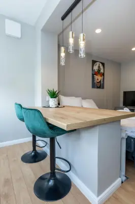 a kitchen with a table and a green chair at Trumpalaikė butų nuoma Kaune prie Klinikų STUDIJA E SELF CHECK IN in Kaunas