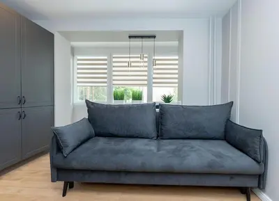 a blue couch in a living room with a window at Trumpalaikė butų nuoma Kaune prie Klinikų STUDIJA E SELF CHECK IN in Kaunas