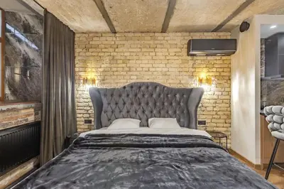 a bedroom with a large bed and a brick wall at Basanavičiaus apartament in Vilnius