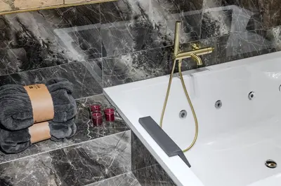 a bathroom with a white tub and a gold faucet at Basanavičiaus apartament in Vilnius