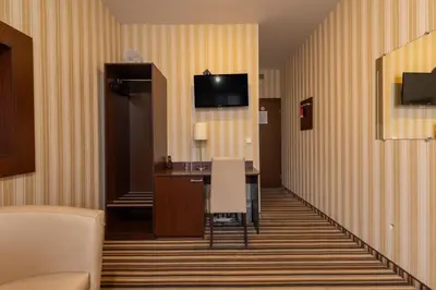 a hotel room with a desk and a television on the wall at City Rooms by Lollo Stay in Vilnius