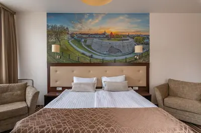 a bedroom with a large bed and two chairs at City Rooms by Lollo Stay in Vilnius