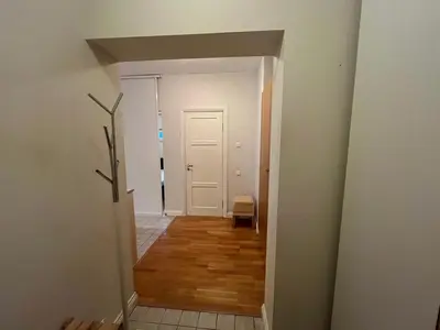 a hallway leading into a room with white walls and wood floors at V13 Apartment in Old Town in Vilnius