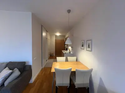 a living room with a wooden table and white chairs at V13 Apartment in Old Town in Vilnius