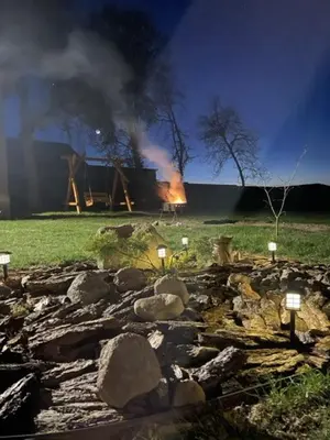 a house on fire in a field with rocks at Sodyba Pušyno kelias