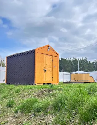 a wooden shed with a door in a field at Sodyba Pušyno kelias