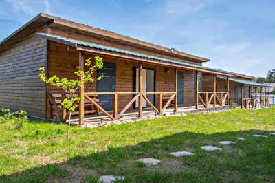 a log cabin with a porch and green grass at Sodyba Pušyno kelias