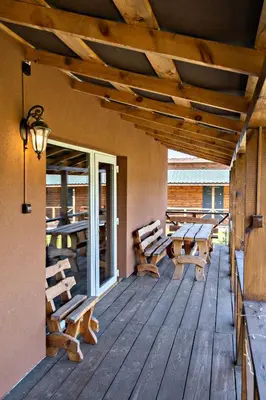 a wooden deck with benches and tables on a house at Sodyba Pušyno kelias