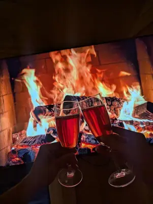 two people holding glasses of wine in front of a fireplace at Jack namai 2 in Puodžiai
